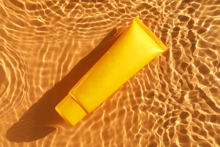 Tube with moisturizing cream in water on orange background, top viewの写真素材