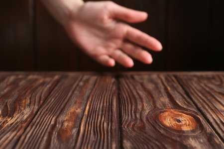Woman holding hand above wooden table, selective focus. Space for textの写真素材