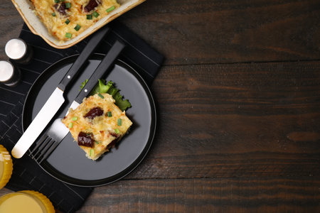 Tasty sausage casserole with green onions and cutlery served on wooden table, top view. Space for textの写真素材