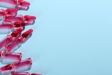 Glass ampoules with liquid on light blue background, top view. Space for textの写真素材