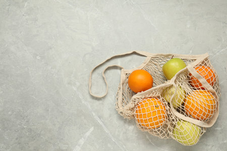 String bag with fresh fruits on gray marble background, top view. Space for textの写真素材