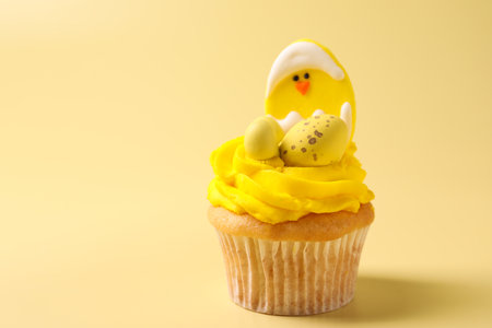 Tasty decorated Easter cupcake on pale yellow background, closeup. Space for text