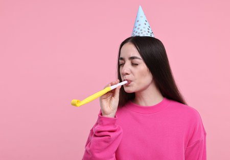 Woman in party hat with blower on pink backgroundの写真素材