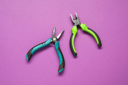 Two pliers on purple background, flat lay