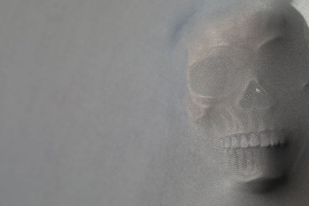 Silhouette of creepy ghost with skull behind cloth, space for textの写真素材