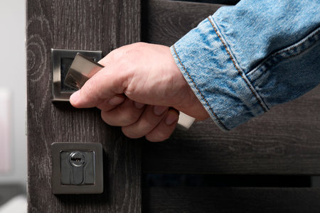 Man opening wooden door indoors, closeup of hand on handle