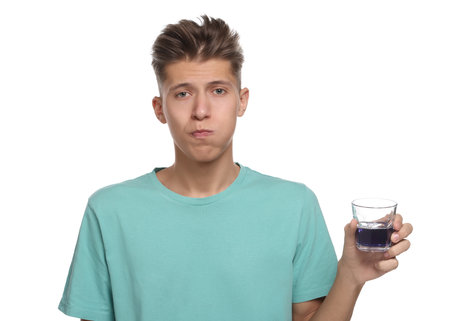 Young man using mouthwash on white backgroundの写真素材