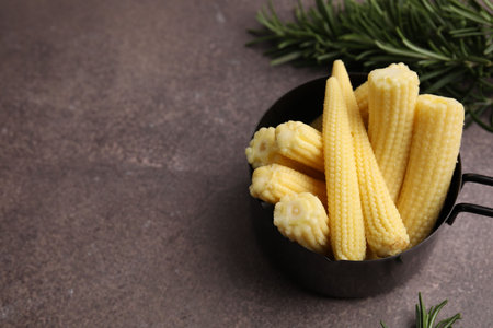 Tasty fresh yellow baby corns in dish on brown table, above viewの写真素材