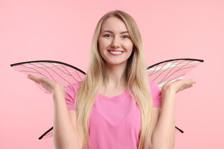 Beautiful girl in fairy costume with wings on pink backgroundの写真素材