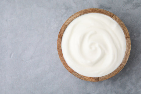 Delicious natural yogurt in bowl on gray table, top view. Space for text