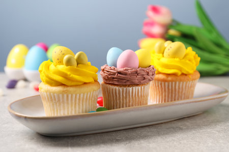 Tasty decorated Easter cupcakes on gray table, closeup