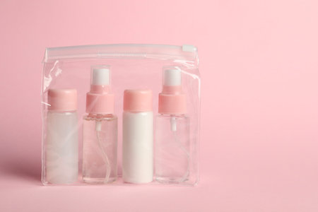 Cosmetic travel kit in plastic bag on pink background. Space for textの写真素材