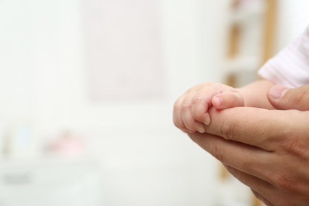 Father with his little baby at home, closeup of hands. Space for textの写真素材