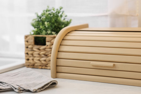 Wooden bread box and houseplant on white marble countertop in kitchen, closeup