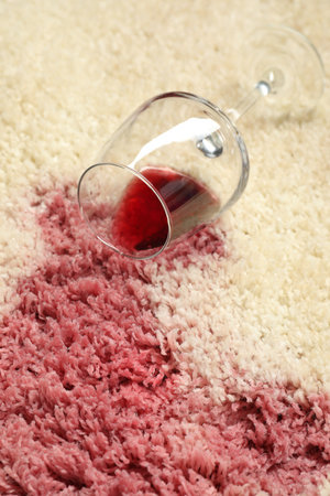 Overturned glass and spilled red wine on beige carpet, closeupの写真素材