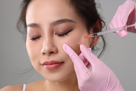 Woman getting facial injection on grey background, closeupの写真素材