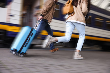 Being late. Couple with suitcase running after train on station, closeup. Motion blur effectの写真素材