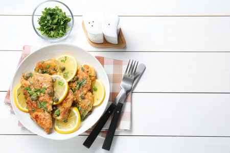Delicious chicken piccata served on white wooden table, flat lay. Space for textの写真素材