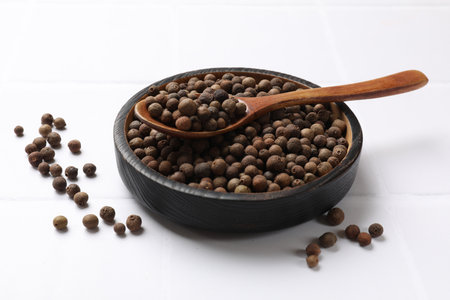 Dry allspice berries (Jamaica pepper) on white tiled table