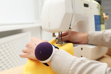 Seamstress working with sewing machine indoors, closeup