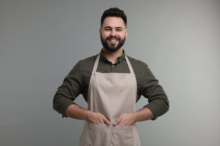Smiling man in kitchen apron on grey background. Mockup for designの写真素材