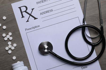 Medical prescription form, stethoscope and pills on wooden table, flat layの写真素材
