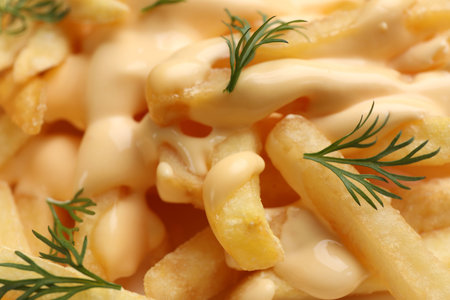 Delicious French fries with cheese sauce and dill as background, closeup