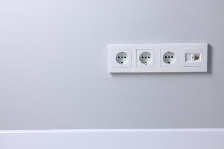 Electric power sockets on light gray wall indoors, space for textの写真素材