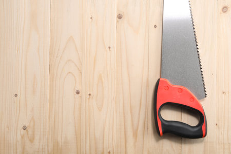Saw with colorful handle on wooden background, top view. Space for textの写真素材