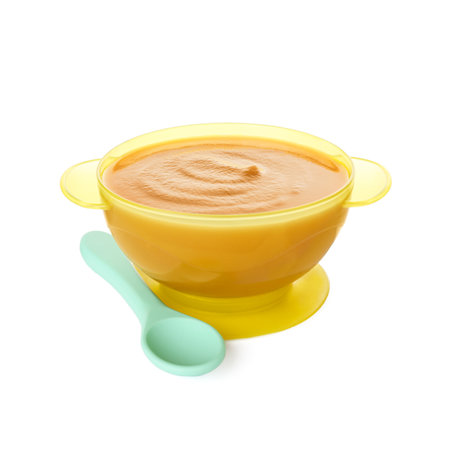 Tasty baby food in bowl and spoon isolated on whiteの写真素材