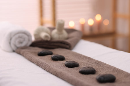 Towel with arranged spa stones on massage table in recreational center, closeupの写真素材