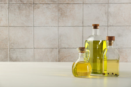 Vegetable fats. Different oils in glass bottles on white wooden table against tiled wall, space for textの写真素材
