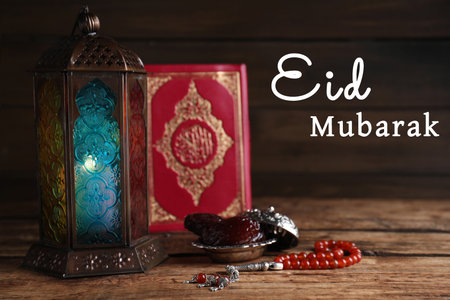 Eid Mubarak greeting card. Arabic lantern, Quran, misbaha and dates on wooden tableの写真素材