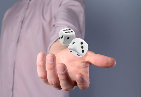 Man throwing white dice on gray background, closeupの写真素材