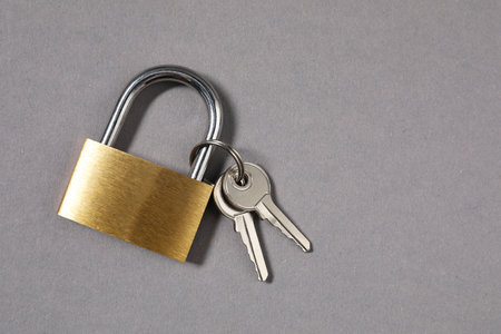 Steel padlock with keys on gray background, top view. Space for text