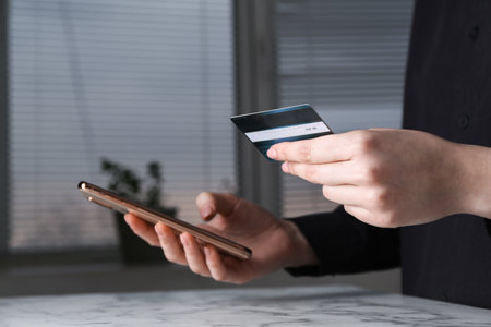 Online payment. Woman with smartphone and credit card at white marble table indoors, closeupの写真素材