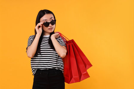 Beautiful woman with shopping bags on yellow background. Space for textの写真素材