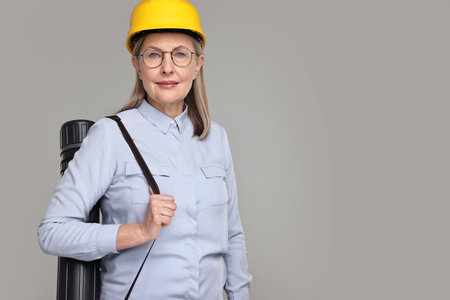 Architect in hard hat with tube on grey background, space for textの写真素材