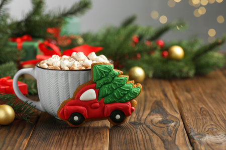 Tasty Christmas cookie in shape of car with fir tree, cocoa with marshmallows and festive decor on wooden table, closeup. Space for textの写真素材