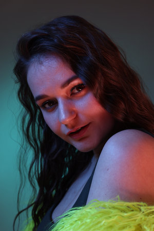 Portrait of beautiful woman in yellow fur coat on dark background with neon lights