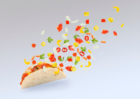 Delicious taco with flying ingredients on gray gradient background