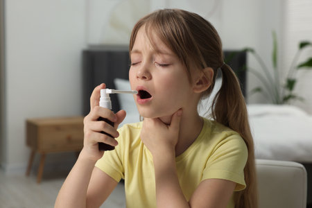 Little girl using throat spray at homeの写真素材