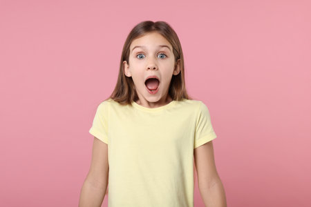 Portrait of surprised girl on pink backgroundの写真素材