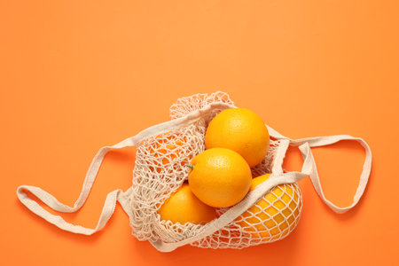 String bag with fresh oranges on color background, top view. Space for textの写真素材