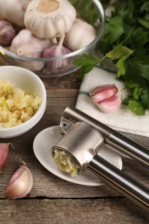 Garlic press, cloves and mince on wooden table, closeupの写真素材