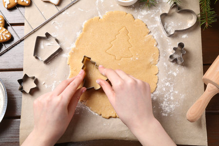 Woman making Christmas cookies with cutters at wooden table, top viewの写真素材