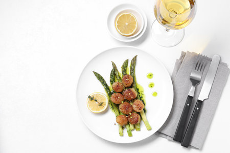 Delicious fried scallops with asparagus, lemon and thyme served on white table, flat lay. Space for textの写真素材