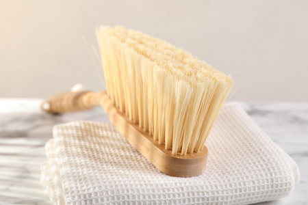 One cleaning brush and rag on white marble table, closeup