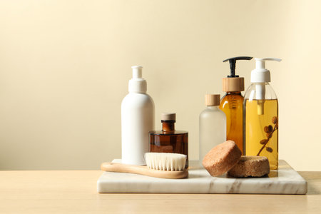 Different bath accessories on wooden table against beige background. Space for text