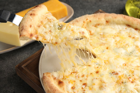 Taking a piece of delicious cheese pizza at gray table, closeup